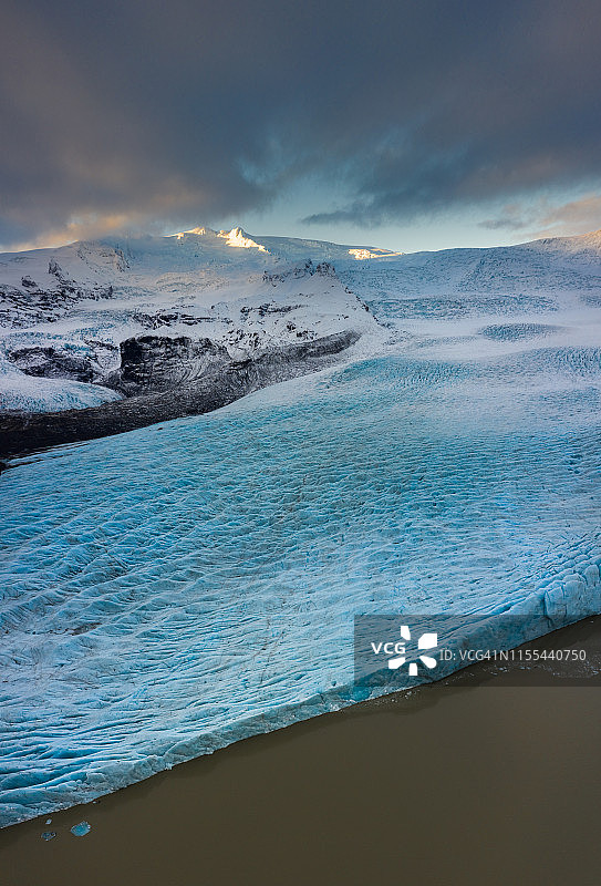 冰山之间的石山在雪和多云的天空图片素材