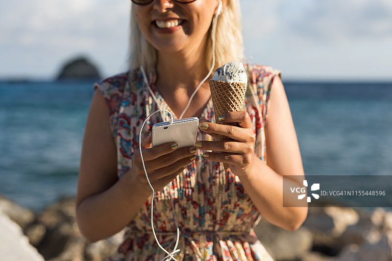 微笑的女人吃着冰淇淋，听着音乐在暑假图片素材