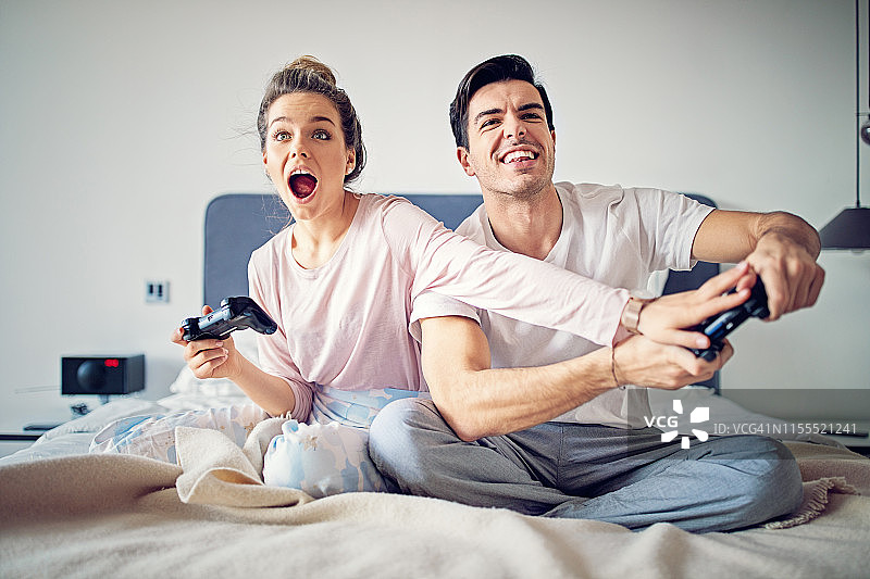 幸福的夫妇在床上玩电子游戏图片素材