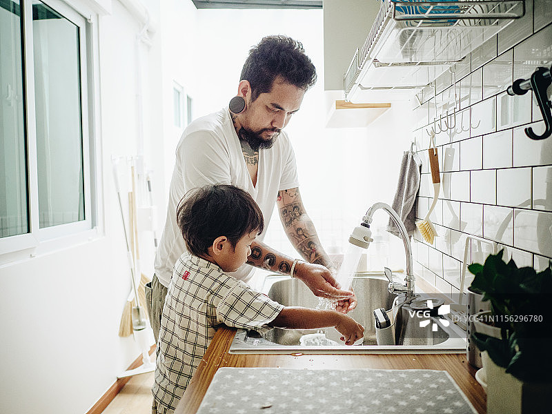 潮爸爸和小宝宝在厨房洗盘子。图片素材