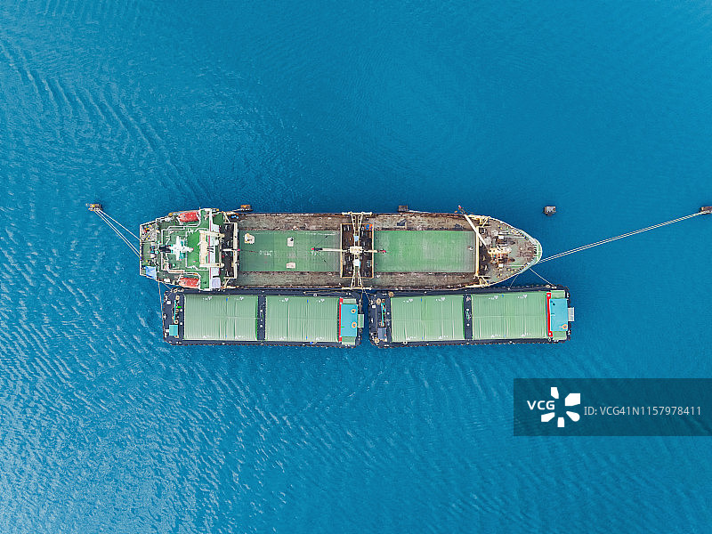 鸟瞰图大米运输船卸货食品到小型船舶物流，进出口，航运或运输。图片素材