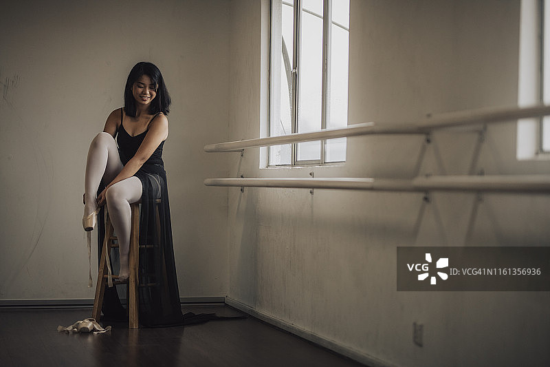 一位年轻的亚洲中国女芭蕾舞演员在芭蕾舞工作室练习芭蕾舞前准备系鞋带图片素材