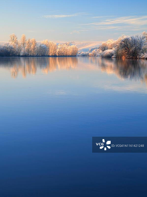 冬季河流景观在萨尔河，树木与霜雪在岸边晨光，水倒影，萨尔河谷自然公园，萨克森-安哈尔特，德国图片素材