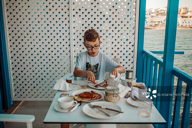 一名少年在希腊海边吃早餐图片素材
