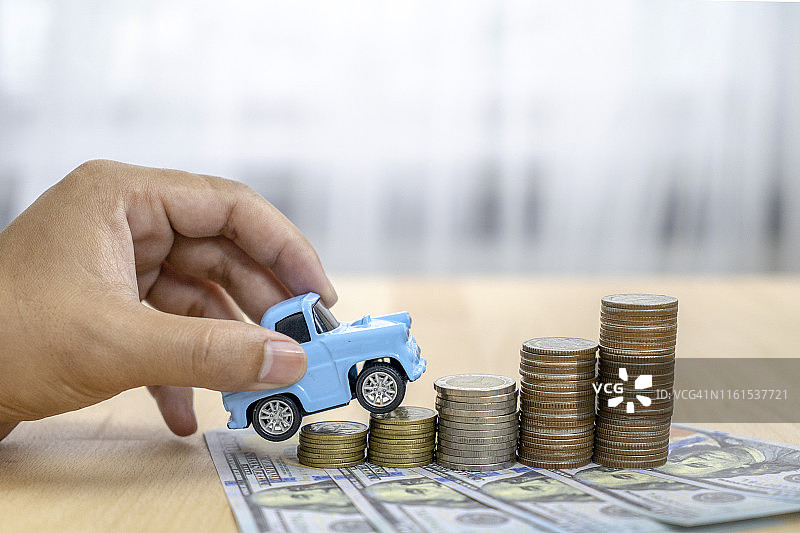 商人和玩具车上的硬币堆叠-保险，贷款和购买汽车的概念图片素材