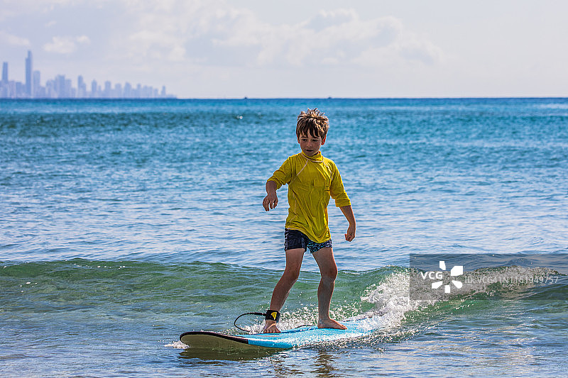 一个小男孩在冲浪板上冲浪图片素材