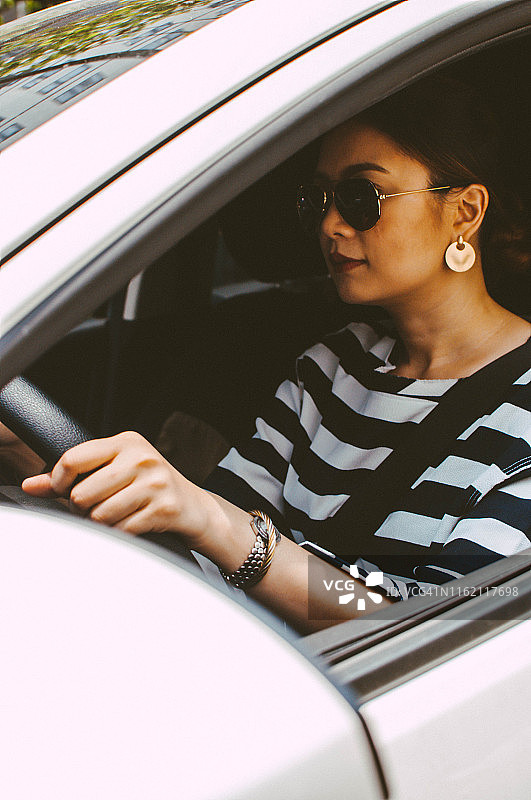 一位年轻的亚洲妇女在白天开车图片素材