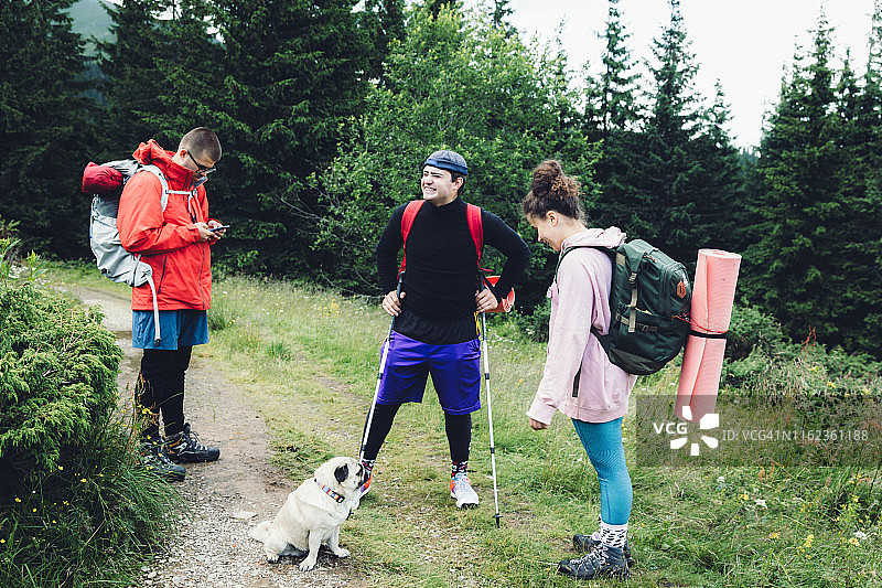 朋友和狗背包客在山里远足图片素材