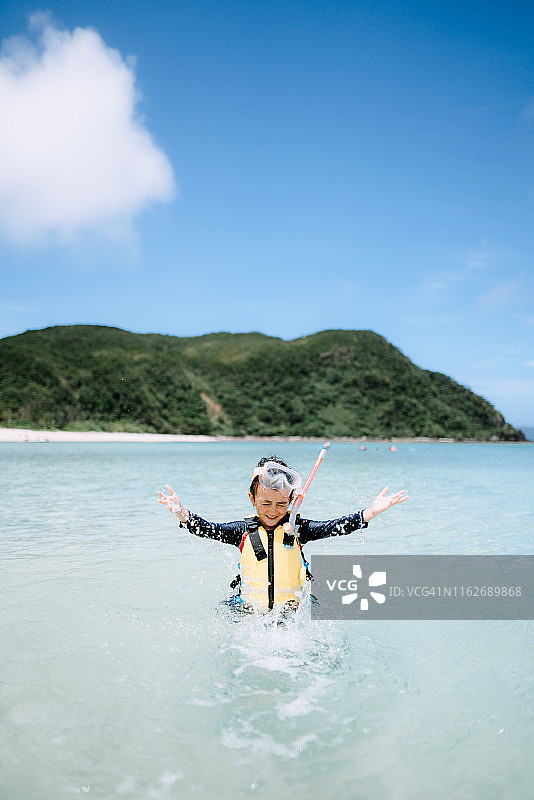 日本冲绳县，一名学龄前女孩戴着面罩泼水图片素材