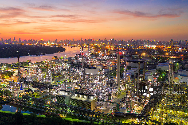 鸟瞰图的石油和天然气炼油厂与大城市市中心在日落期间的背景图片素材