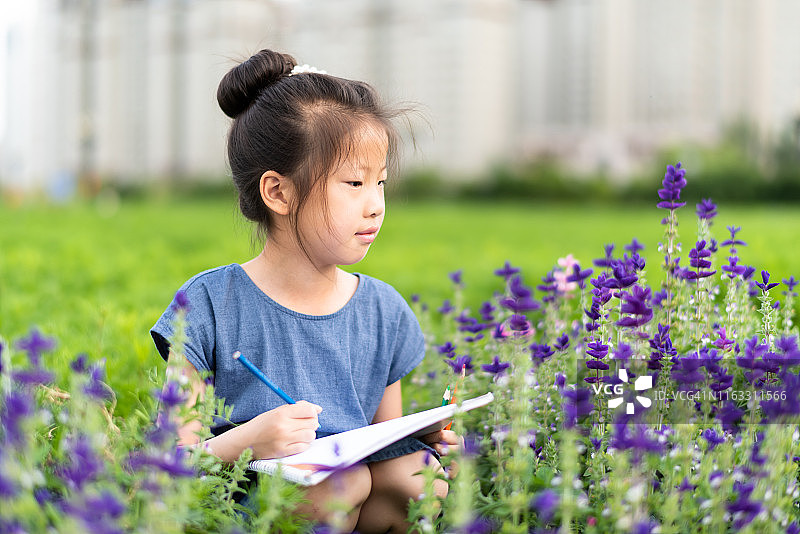 亚洲小女孩在草坪上画画图片素材