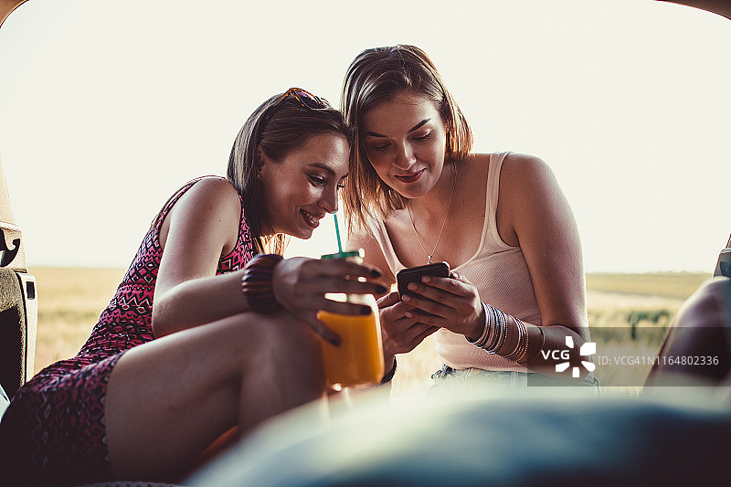 两个快乐的女人在野营旅行中放松时使用手机图片素材