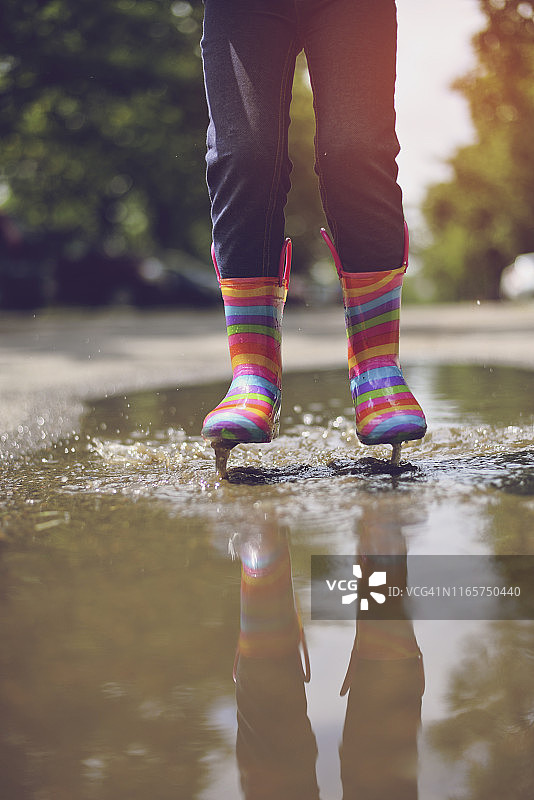 穿着橡胶靴子的孩子的脚。夏天,水坑,雨图片素材