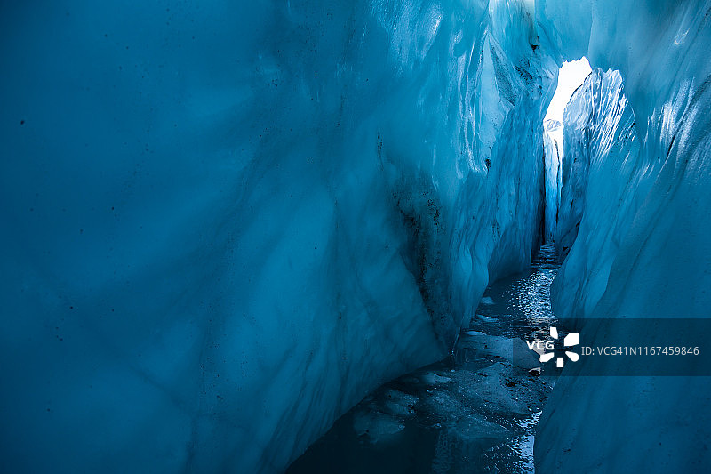 从马塔努斯卡冰川充满水的裂缝里往外看。上面是一座拱形的薄冰桥。图片素材