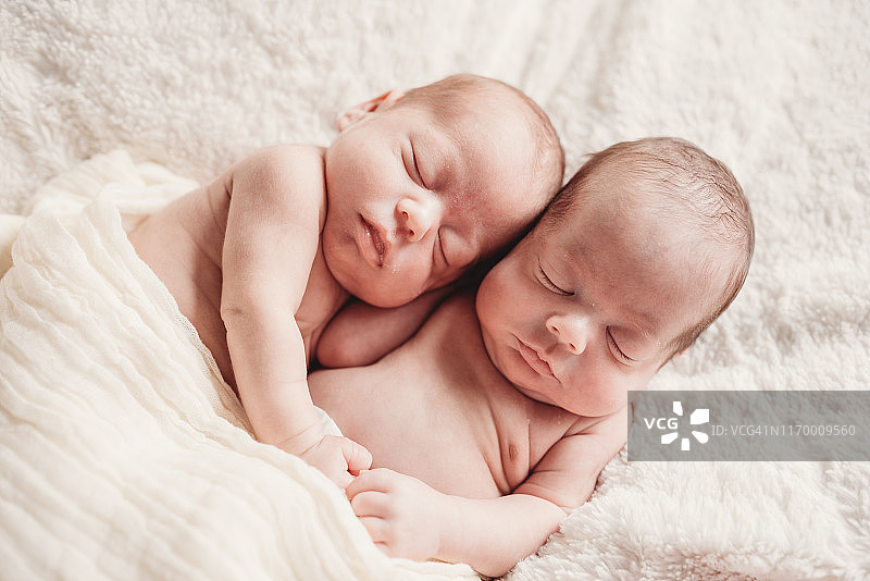 美丽的双胞胎男婴一起睡在白色的毯子上图片素材