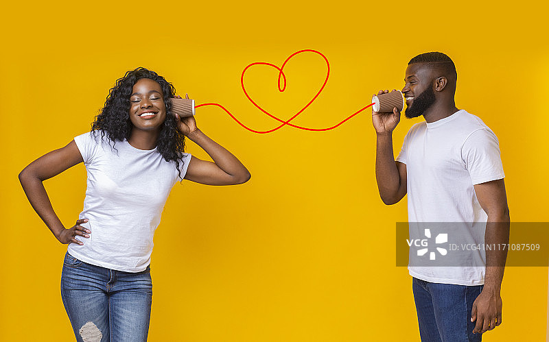 年轻的黑人夫妇可以在黄色背景上打电话图片素材