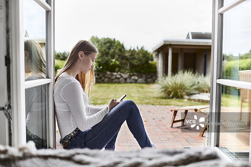 一个年轻女子坐在窗台上用手机图片素材