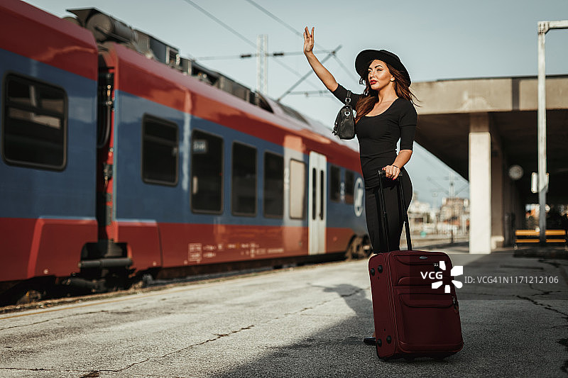 一个年轻女子提着行李箱在火车站图片素材