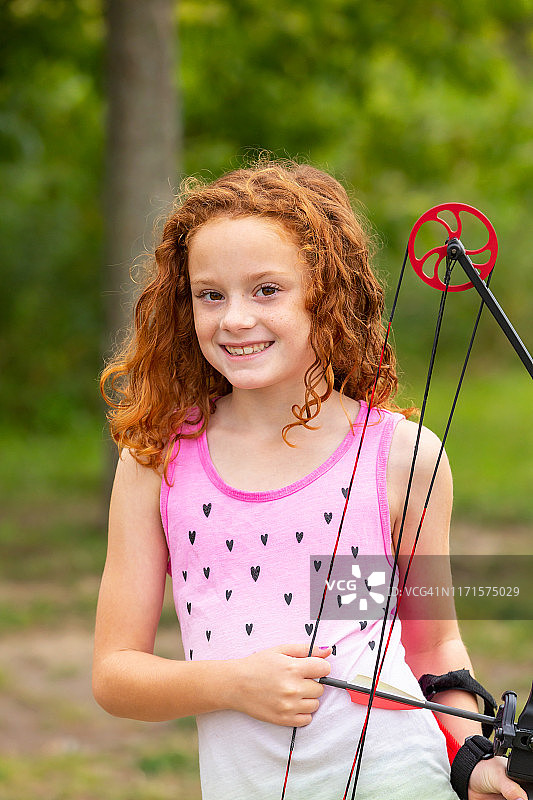 女孩与卷红头发拿着弓和箭图片素材