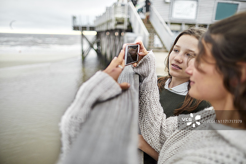 年轻的女人和女孩拿着智能手机在海边图片素材
