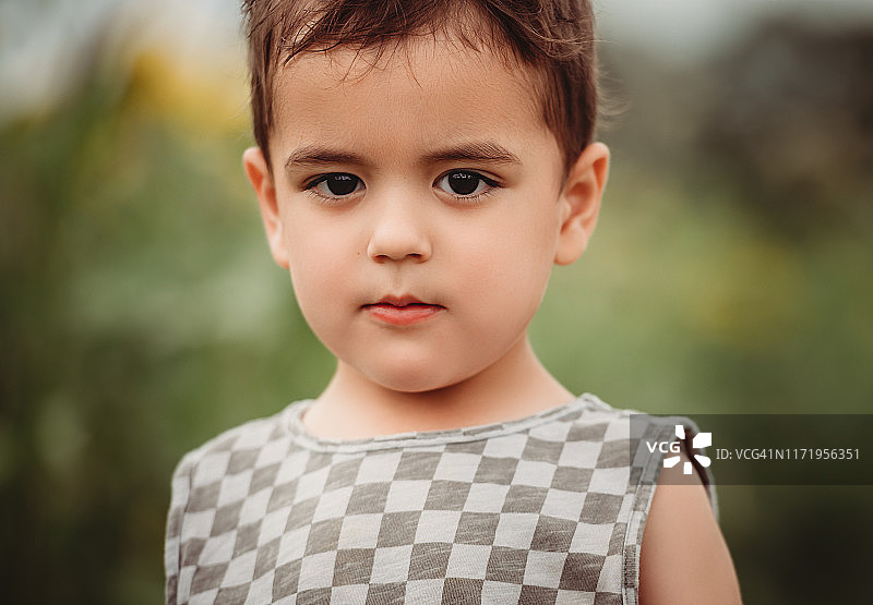 在爱荷华州的向日葵农场里摆姿势的一个3岁的黑发男孩的肖像图片素材