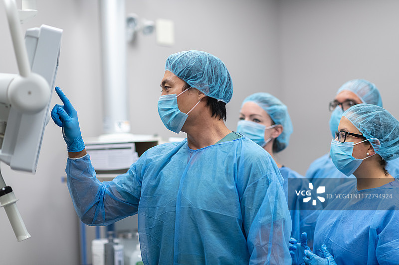 男性外科医生在手术前与手术团队一起评估病人的医疗状况图片素材