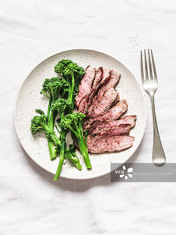 健康饮食午餐-烤牛排和煮西兰花在一个轻的背景，俯视图图片素材