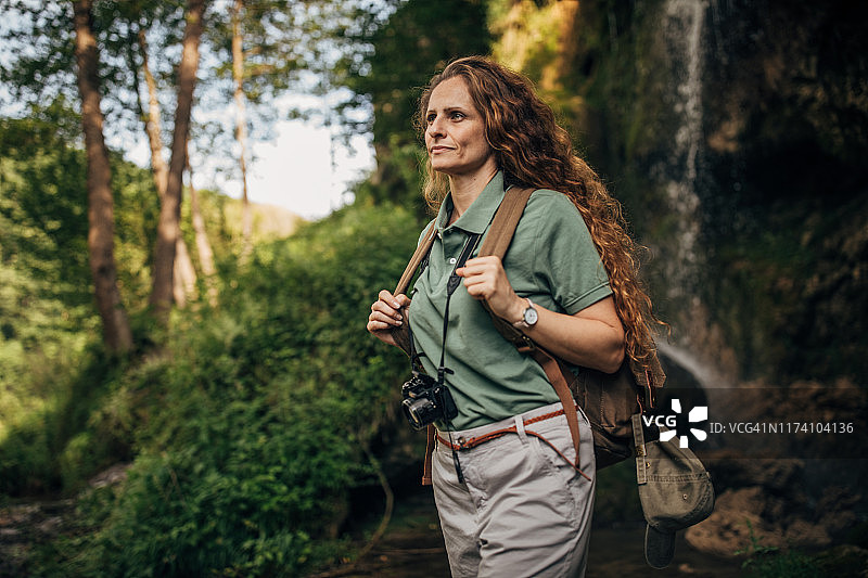 在瀑布边背着背包的女探险家图片素材