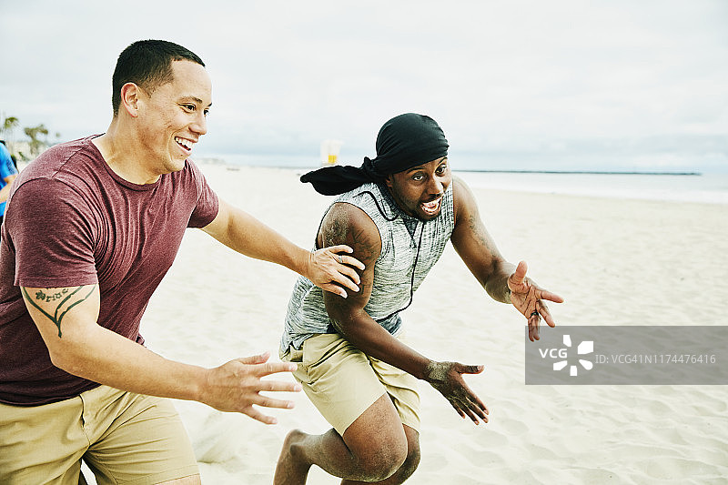 在沙滩上的足球比赛中，微笑的人防守去传球的对方球员图片素材