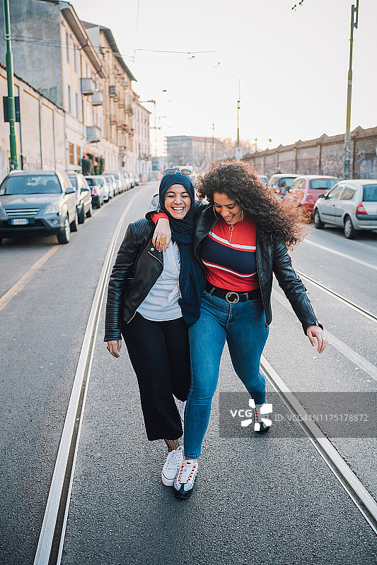 戴头巾的年轻女子和最好的朋友在城市过马路图片素材