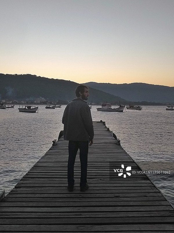 一个人在码头上看日落的海洋- Florianópolis，圣卡塔琳娜州-巴西图片素材