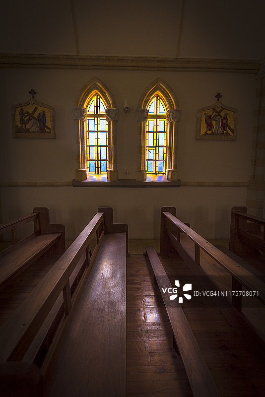 在一个小镇的一个乡村教堂的内部。透过窗户的日光照亮了教堂的长凳。图片素材