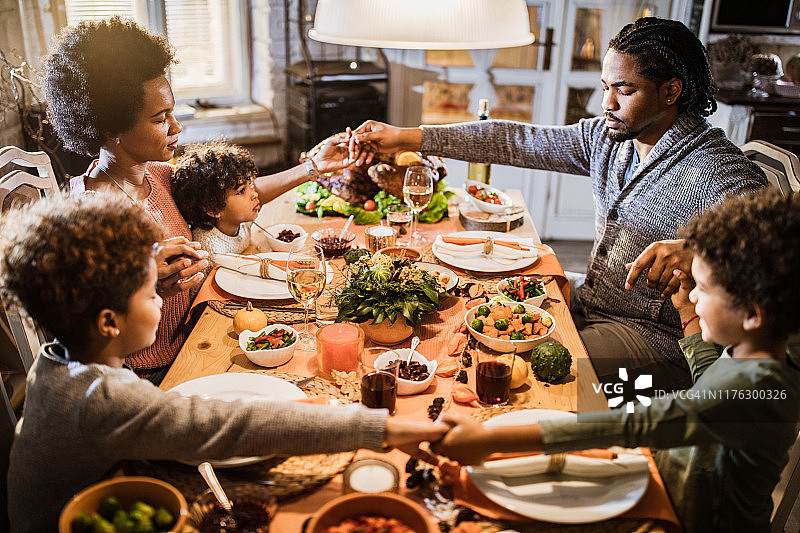 有宗教信仰的黑人家庭在感恩节午餐前在家祷告。图片素材