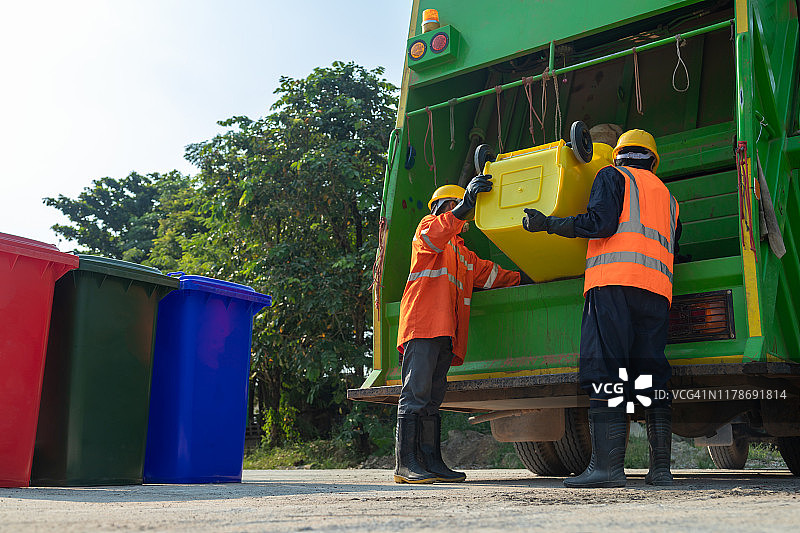 [垃圾收集员]亚洲工人，在泰国的城市垃圾回收车上装载垃圾和垃圾桶。图片素材