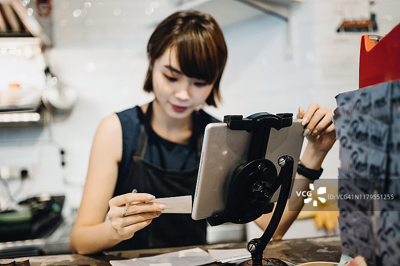 年轻的亚洲女性企业主管理企业财务和做的数字平板电脑在咖啡馆图片素材