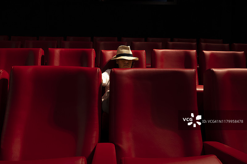 一个戴帽子的女人独自坐在电影院图片素材