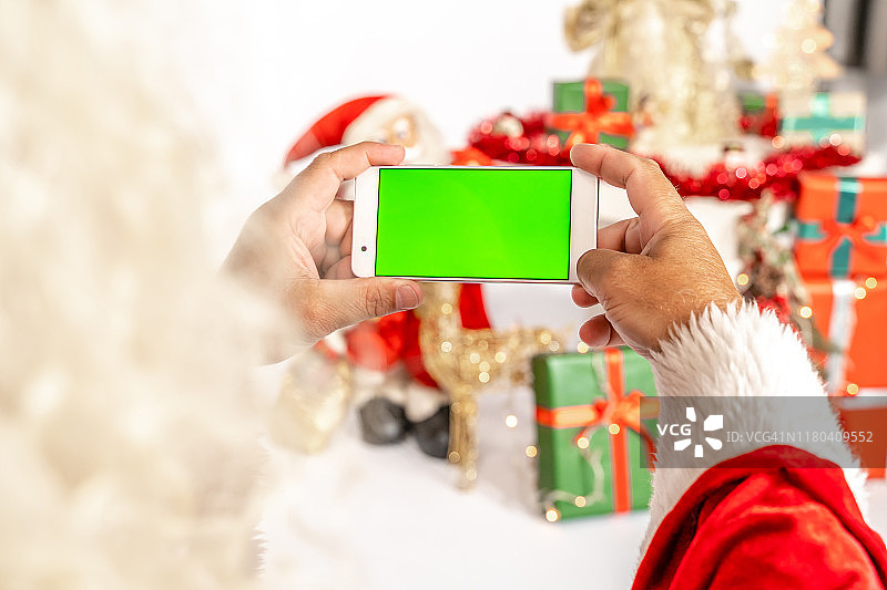 圣诞老人用彩色键绿色屏幕的白色智能手机图片素材