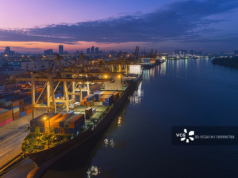 鸟瞰图集装箱货轮在码头商业港口和工作起重机桥装载集装箱的业务物流，进出口，航运或运输。图片素材