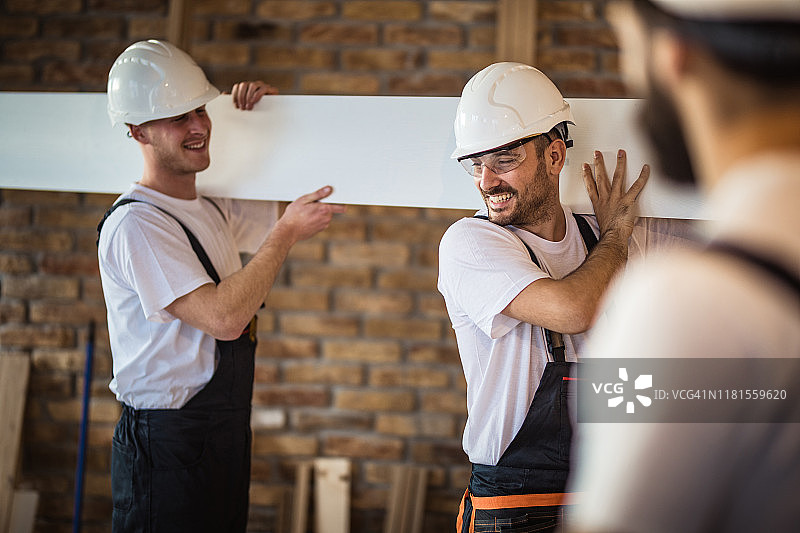 在建筑工地工作时，快乐的体力劳动者与同事交谈。图片素材