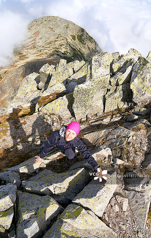 在欧洲的罗马尼亚，一名登山者女孩站在岩石之间试图爬上国家公园里的雷特扎特山。图片素材