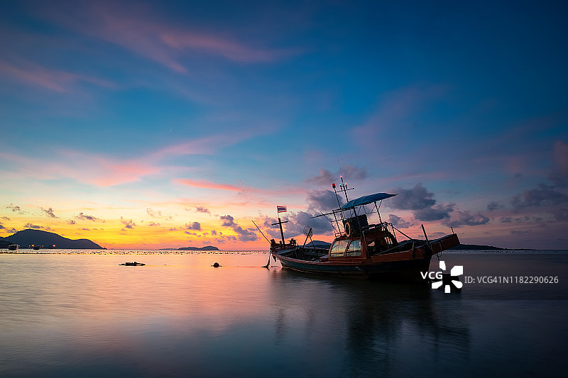 日出时，一艘船停在海滩边图片素材