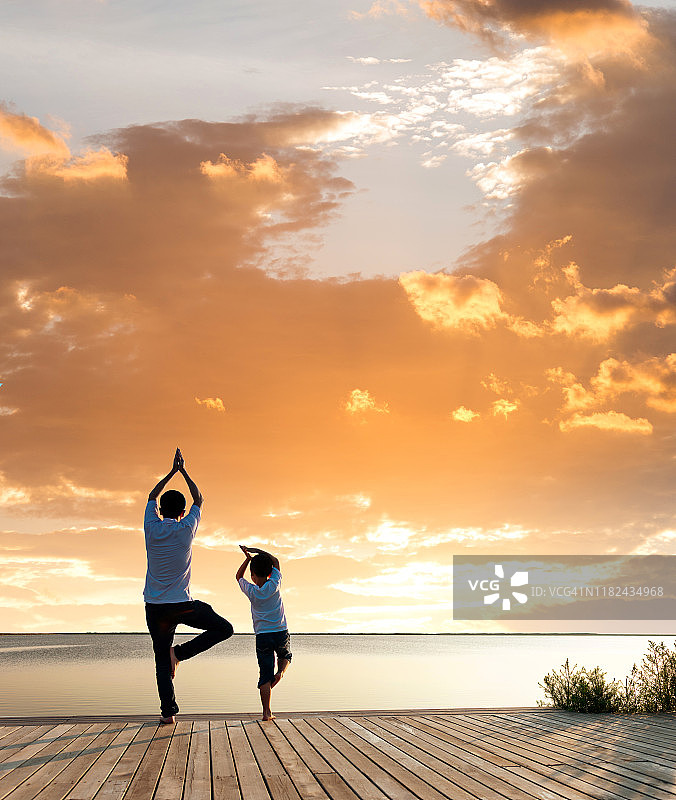 日落时分，父亲和儿子在湖边做瑜伽图片素材