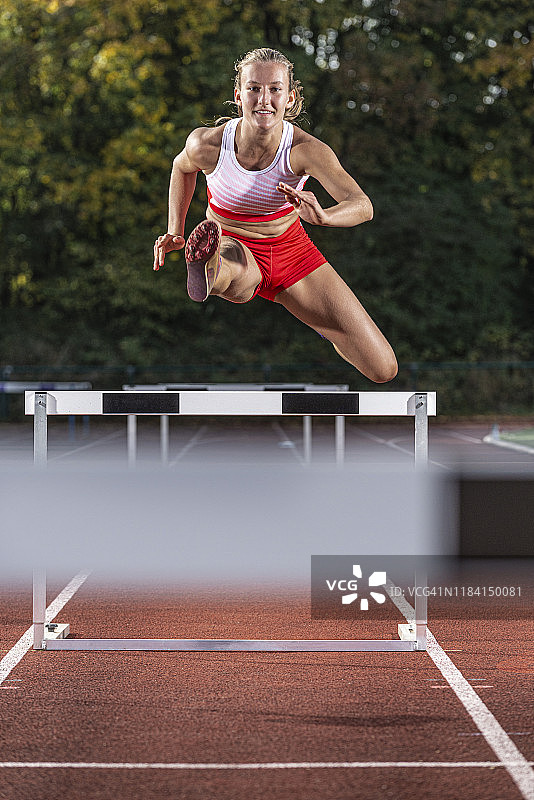 女运动员在跑道上跳过跨栏图片素材