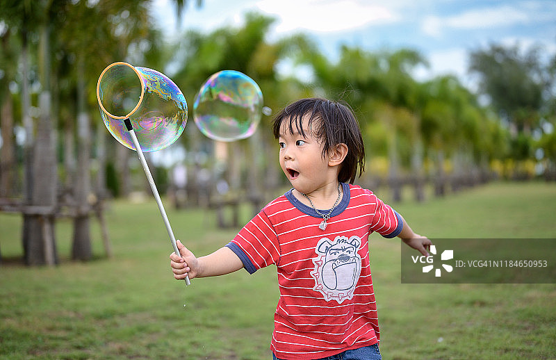 亚洲快乐的小朋友在花园里吹肥皂泡棒图片素材