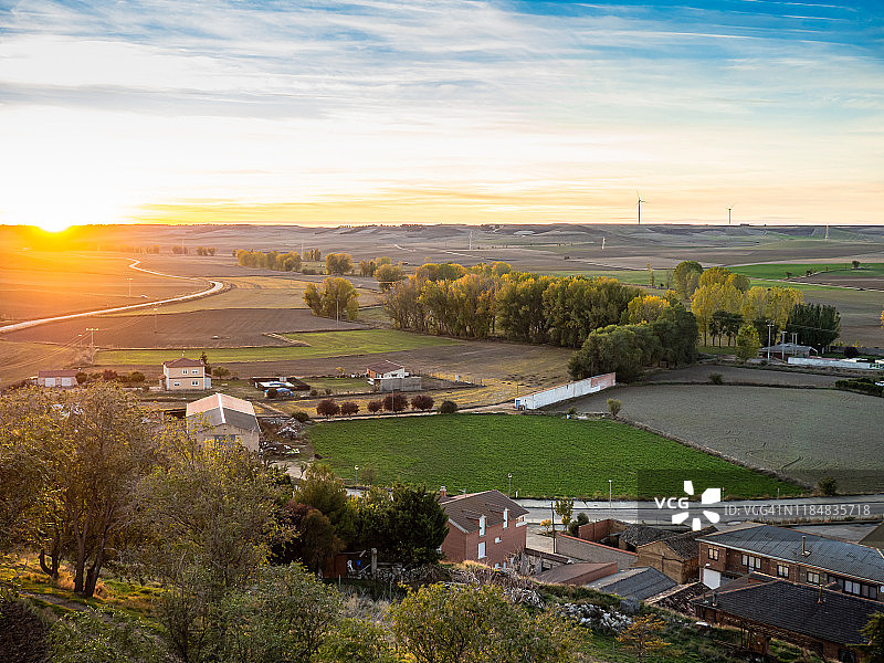 鸟瞰图一个风景优美的秋天景观日落与农田，农村道路，房屋和风力涡轮机在地平线上在西班牙市政Torrelobatón。图片素材