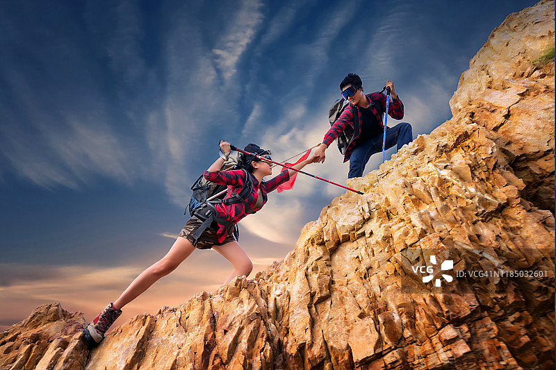 亚洲夫妇徒步登山，帮助登山。团队和领导的概念。度假，露营，旅行和放松的概念。图片素材
