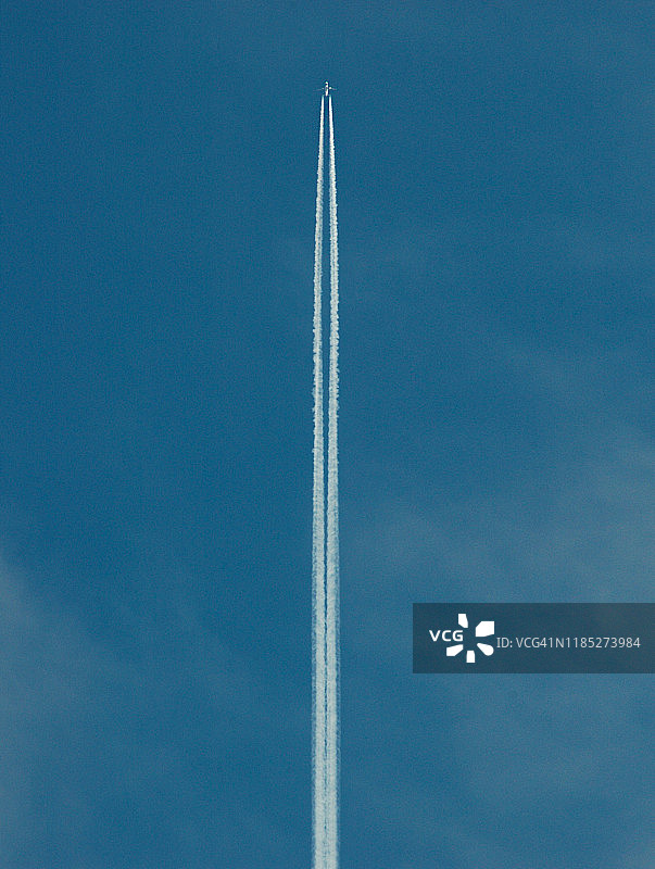 白色的飞机尾迹，在晴朗的蓝天中飞行图片素材