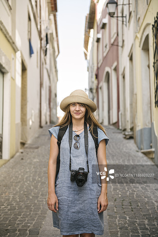 在葡萄牙老城科英布拉的一条小巷里，一个拿着相机的女人的肖像图片素材