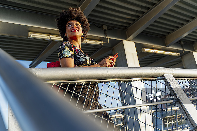 微笑的美国黑人女性，拿着红色的智能手机图片素材