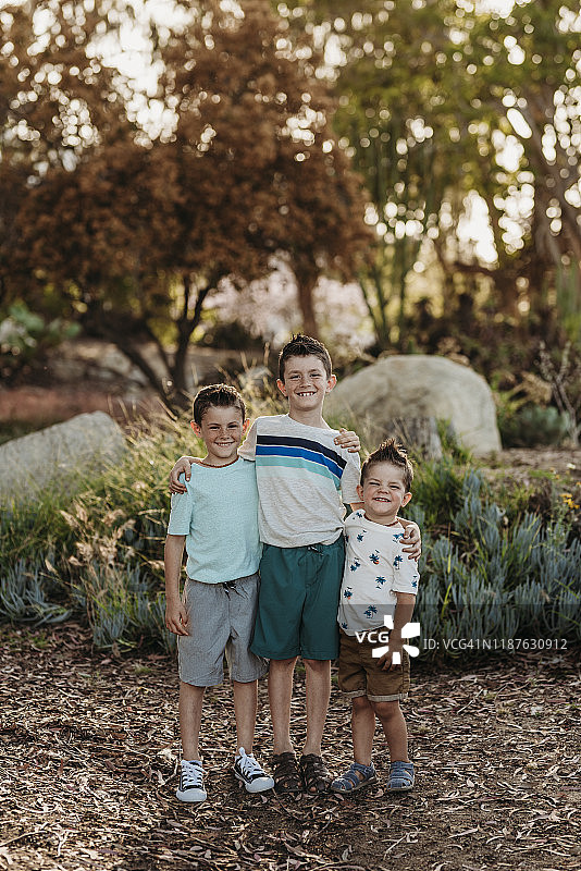 在仙人掌花园里，三兄弟对着相机微笑的肖像图片素材